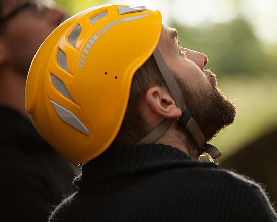 Mann mit Helm schaut im Kletterpark in die Höhe