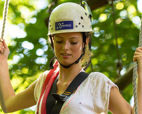 Frau hält sich beim Klettern an Seilen fest