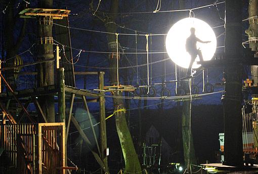 Eine Person klettert im Kletterpark bei Nacht 