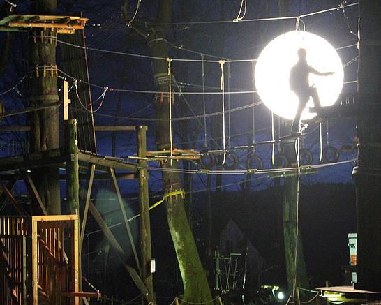 Eine Person klettert im Kletterpark bei Nacht 