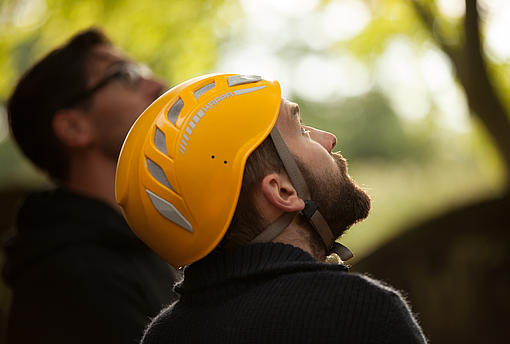 Mann mit Helm schaut im Kletterpark in die Höhe