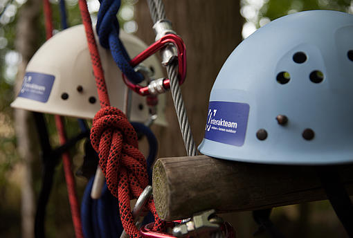 Helme, Seile und Karabiner liegen an einem Kletterelement