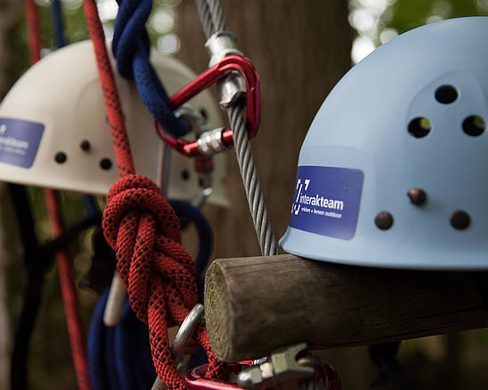 Helme, Seile und Karabiner liegen an einem Kletterelement