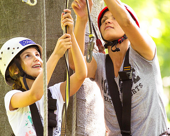 Mutter und Tochter klinken sich im Kletterpark in ein Kletterelement ein