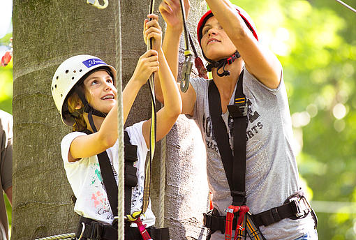 Mutter und Tochter klinken sich im Kletterpark in ein Kletterelement ein