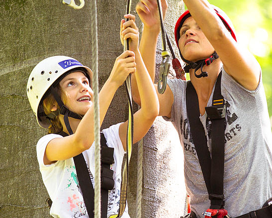 Mutter und Tochter klinken sich im Kletterpark in ein Kletterelement ein