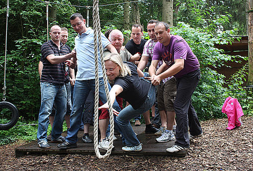 Ein Team versucht gemeinsam ein Seil zu erreichen
