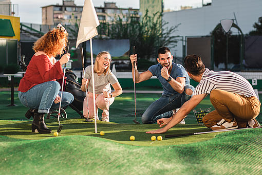 Eine Gruppe kniet vor einem Minigolfloch