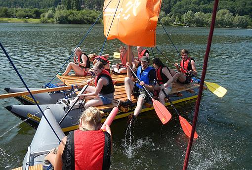 Ein Team unterwegs auf einem Fluss mit einem Floß