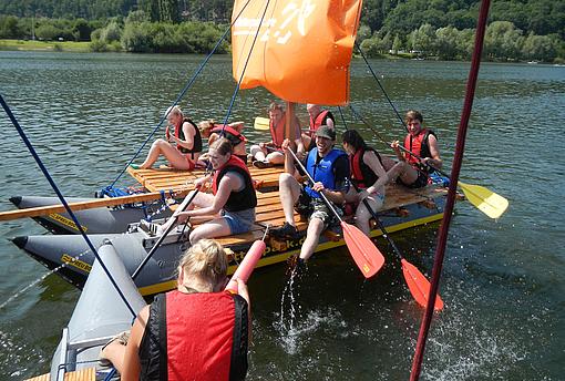 Ein Team unterwegs auf einem Fluss mit einem Floß